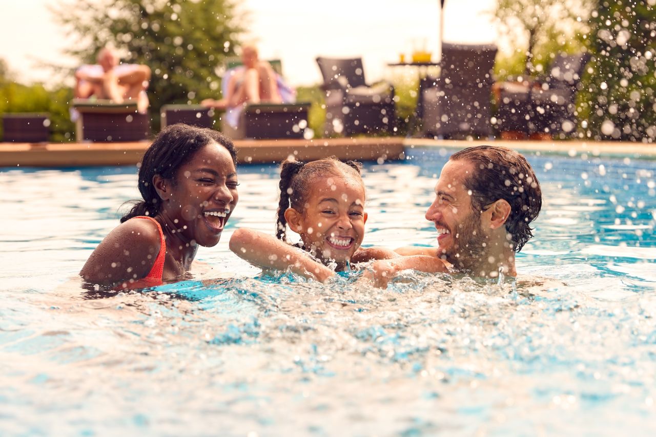 A family splashes around in their hotel pool during their summer holiday